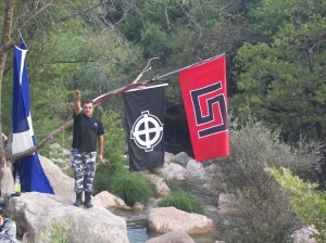 O δολοφόνος του Παύλου Φύσσα, Γεώργιος Ρουπακιάς, στη διάρκεια εκπαίδευσης, υπό τις σημαίες με τα σύμβολα της Χρυσής Αυγής. Φωτογραφία από τη δικογραφία.